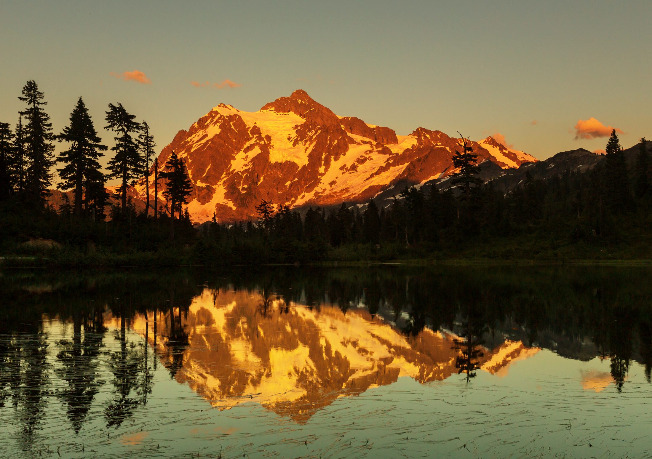 Alpenglow lighting the peak of Mount Shuksan, reflected in a still alpine lake